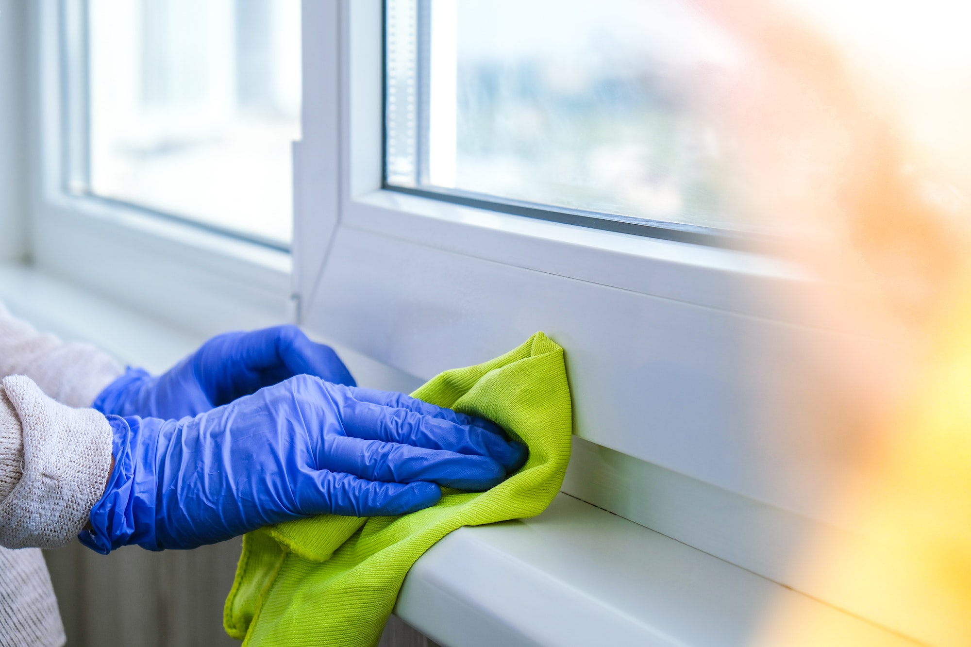 Cleaning the windowsill wiping dust by blue microfiber cloth for cleaning on the glass window rail B