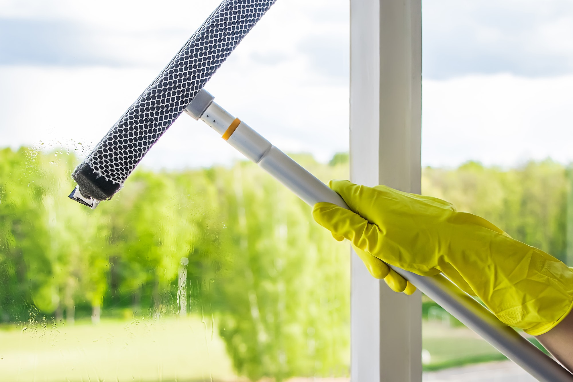 Window cleaning. A woman sprays a cleaner on glass. Housework concept.