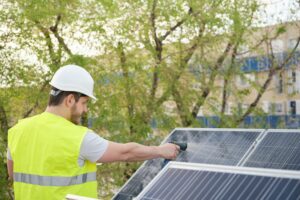 Technician cleaning solar panels with a hose.