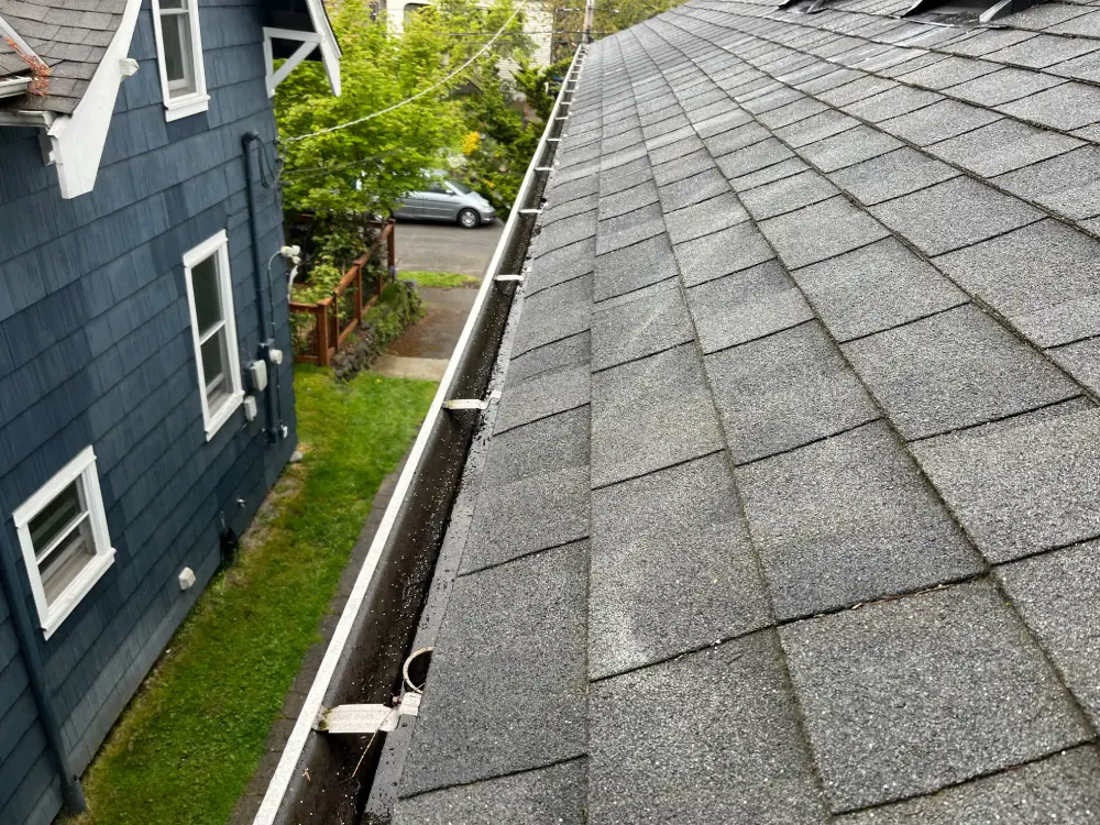 Close-up view of a clean residential gutter after thorough gutter cleaning, showing no debris or clogs along the roofline.