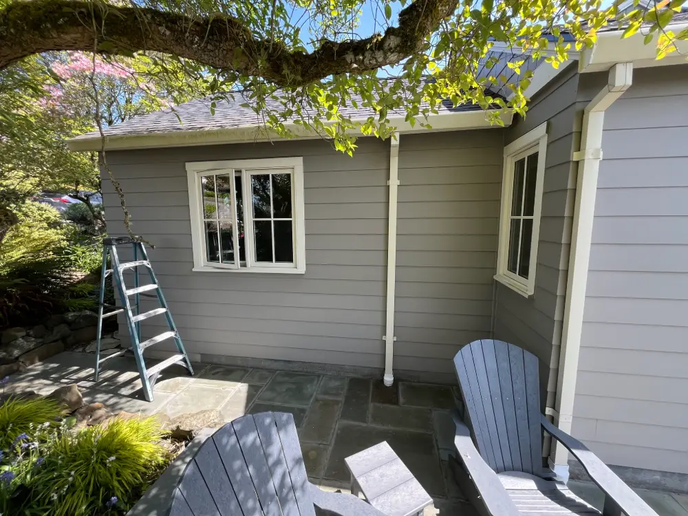 Backyard view of a cozy patio with spotless windows and clean siding, showing the difference after expert window cleaning.