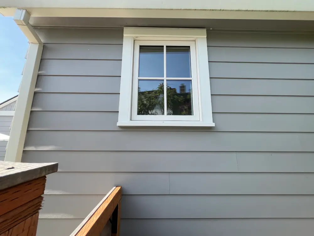 Freshly cleaned window with clear reflections and bright siding showing results of professional window cleaning.