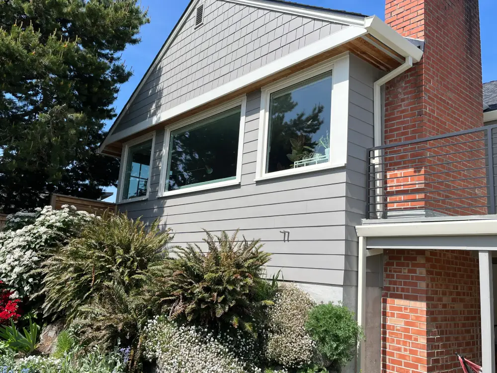 A home exterior with large clear windows reflecting the blue sky, highlighting the results of professional window cleaning.